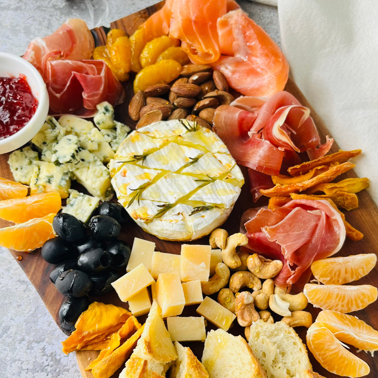 Красивая большая винная тарелка с запечённым камамбером, мандаринами и хамоном